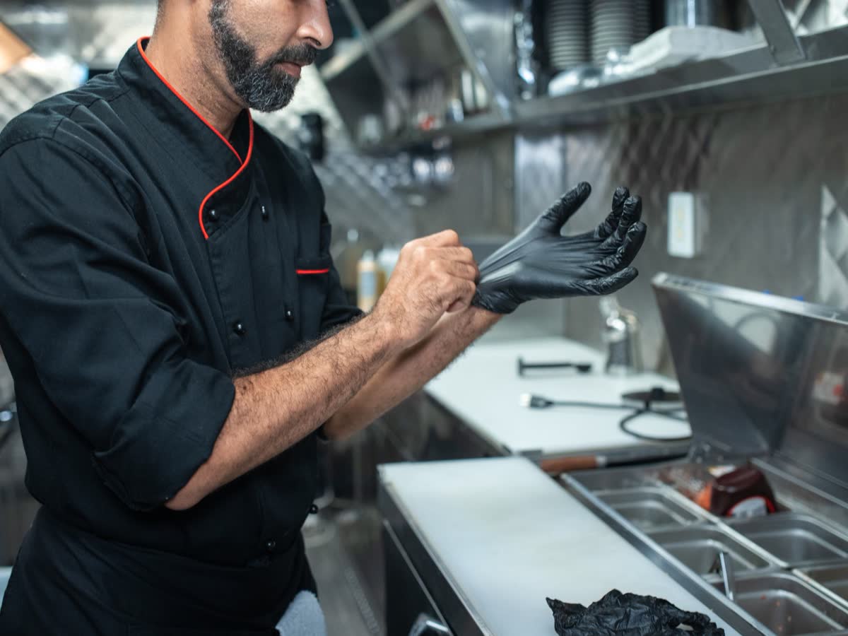 Operatore alimentare con guanti al banco di preparazione